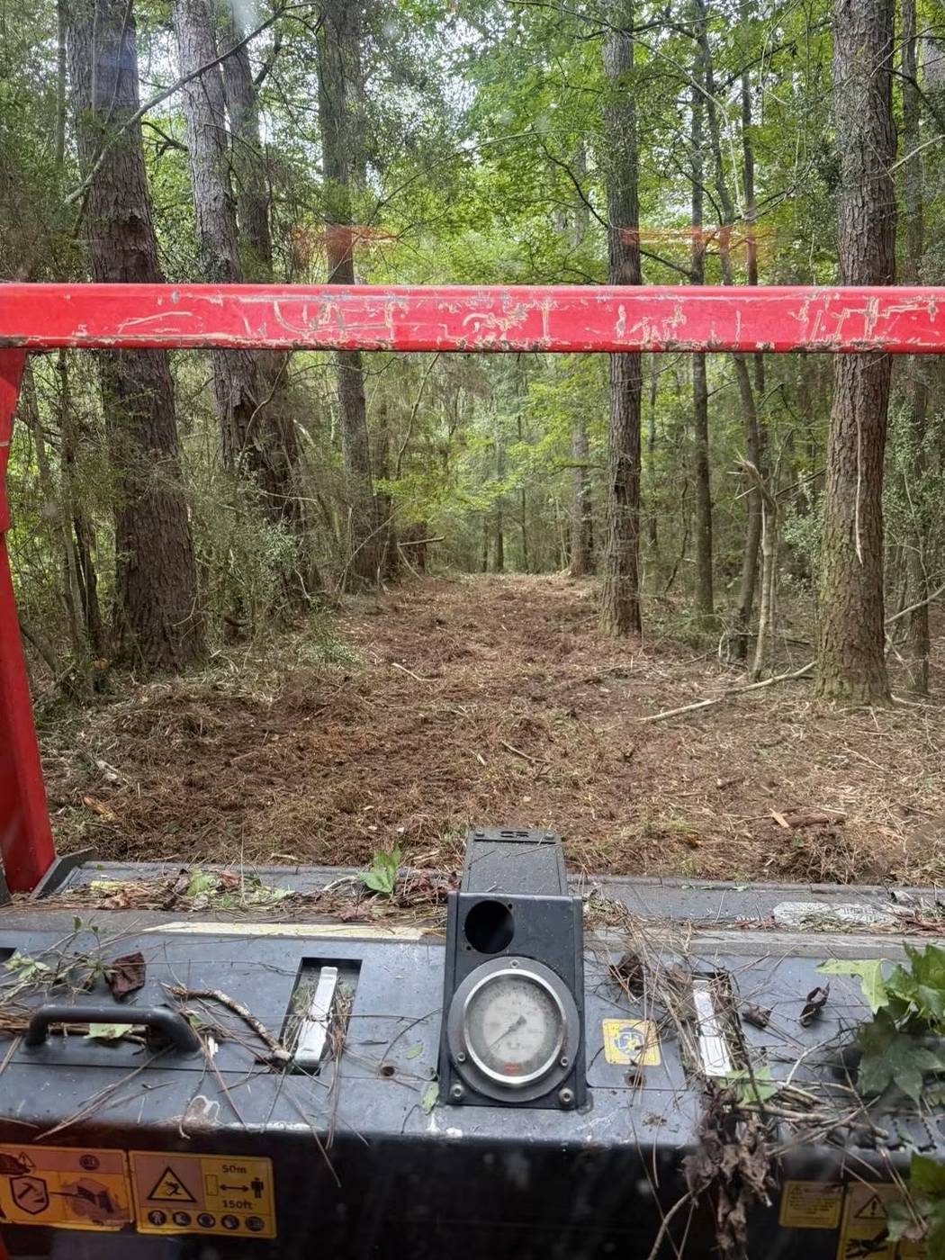 View from land clearing equipment showing a freshly cleared path through the woods