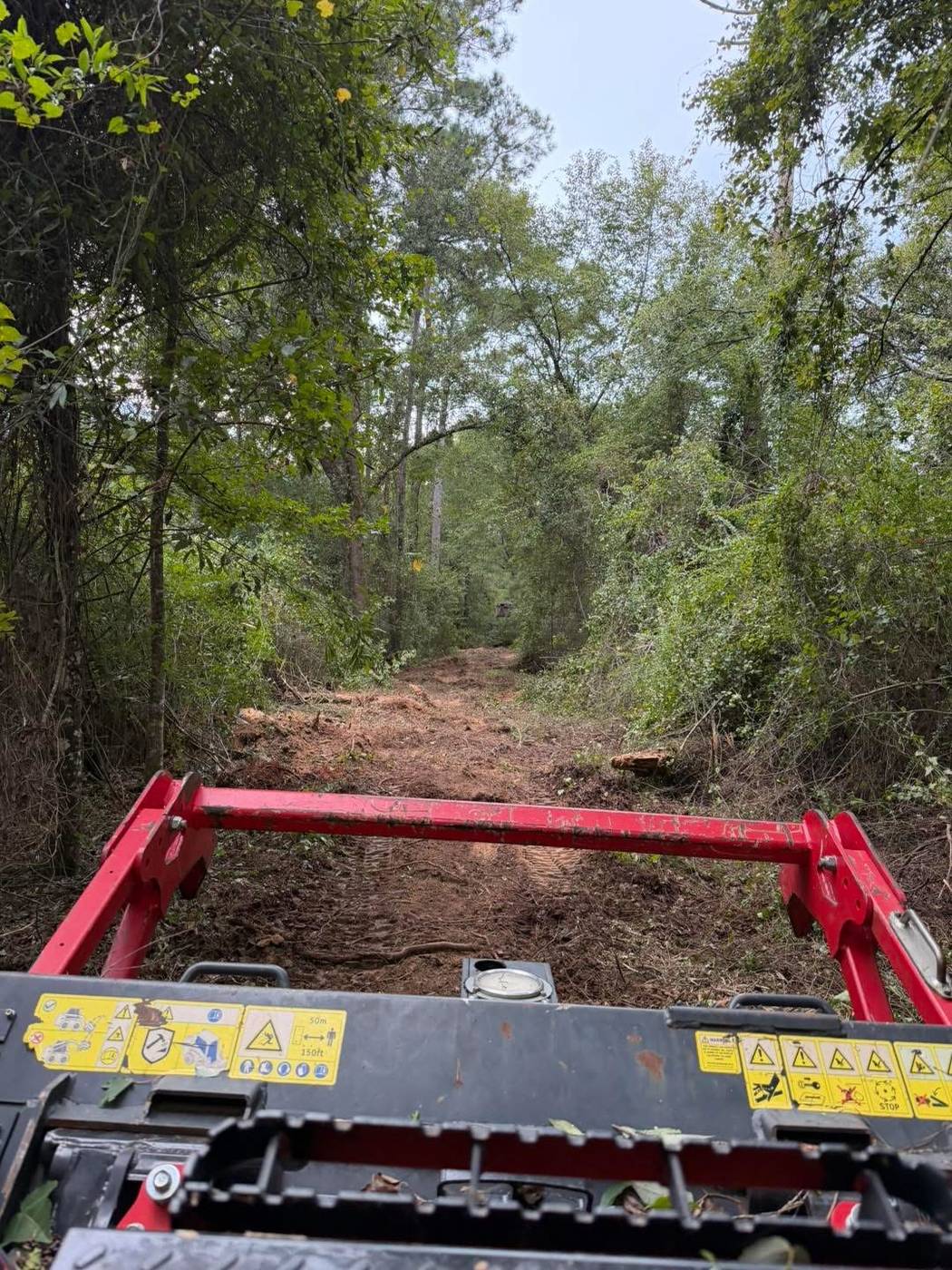 Land clearing equipment cutting a trail through dense forest